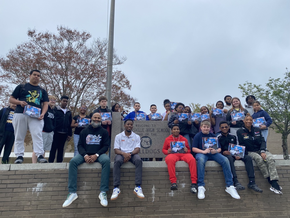 MHS and MMS students pose outside in front of an MHS sign with NASCAR driver Rajah Caruth and members of the Wendell Scott Foundation