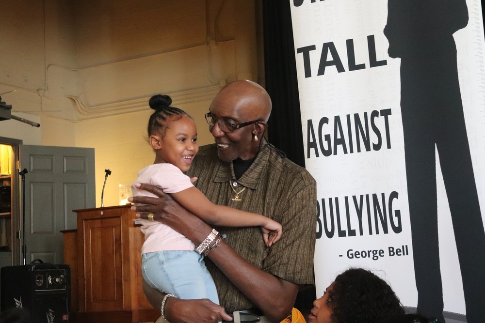 George Bell holds a smiling elementary school student