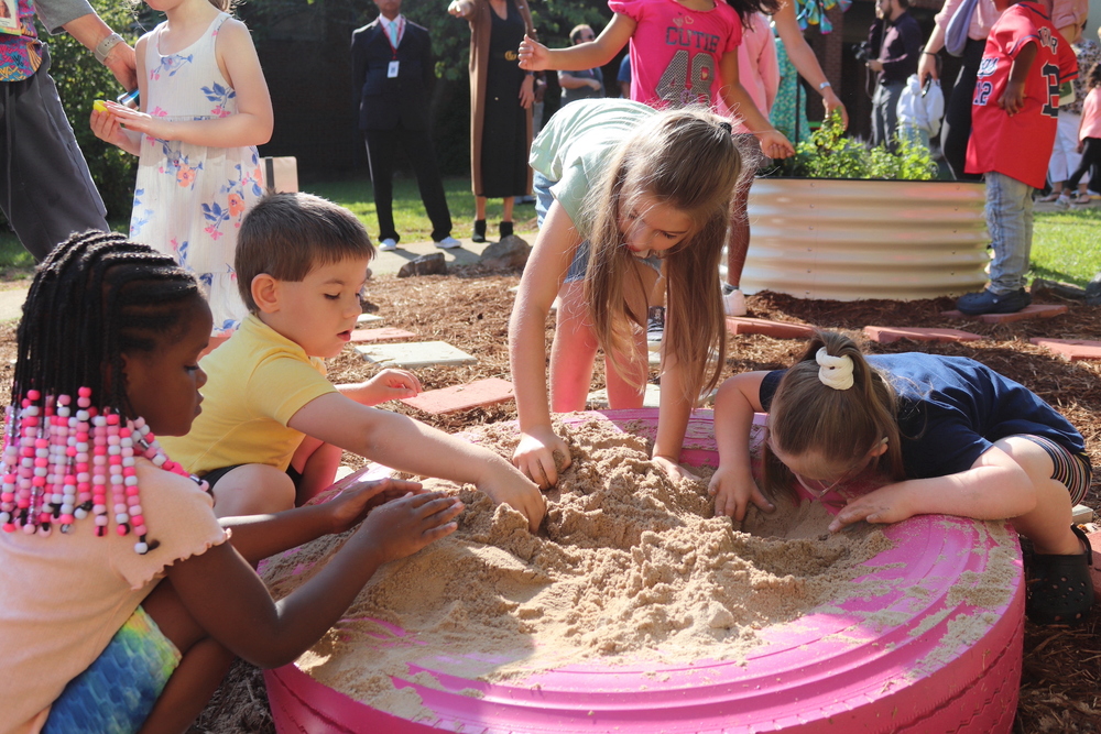 AHES students play in sand in the sensory garden