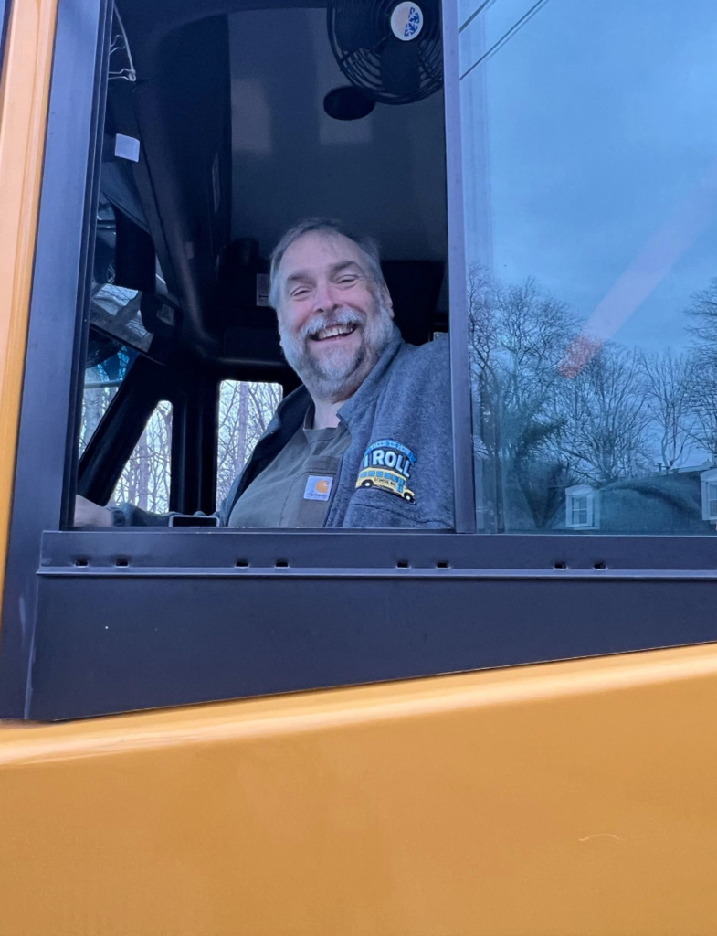 Bus driver smiling out of school bus window