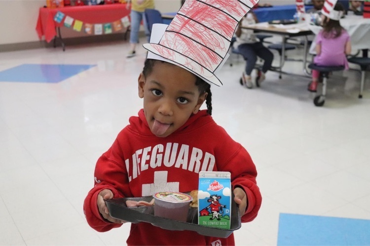 Clearview student with a tray of green eggs and ham in Dr. Seuss hats