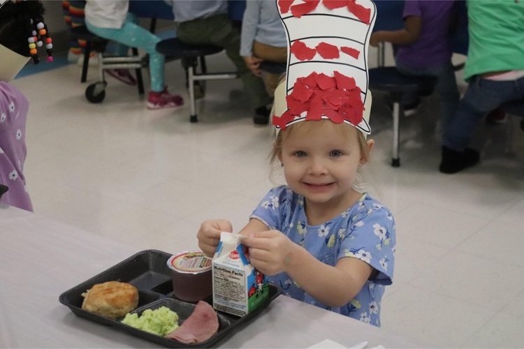 Clearview student eating green eggs and ham in Dr. Seuss hat