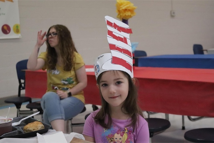 Clearview student eating green eggs and ham in Dr. Seuss hat