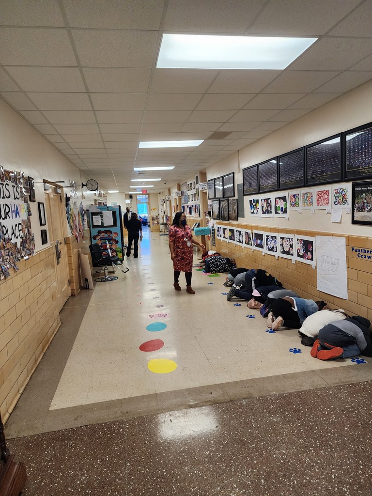 Students kneel and cover their heads in the hallway