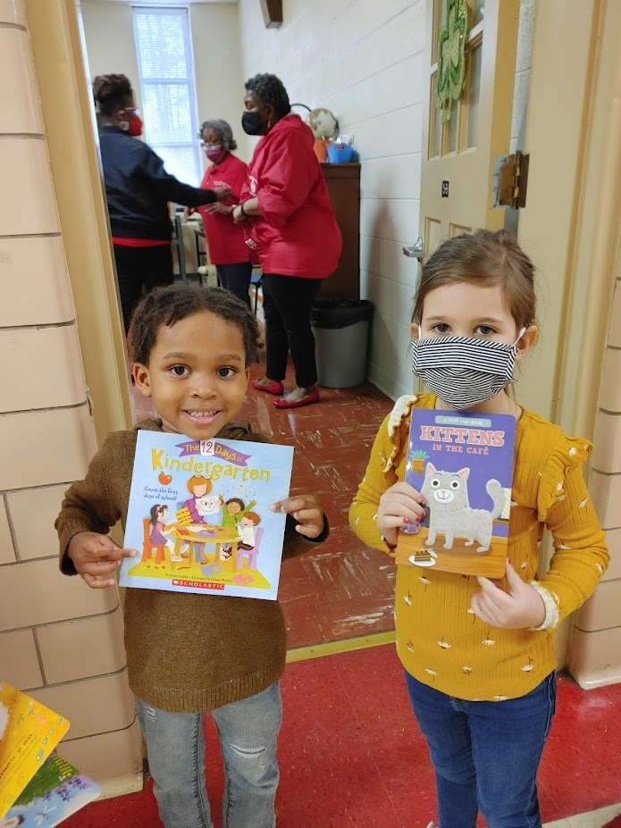 Two preschool students hold books