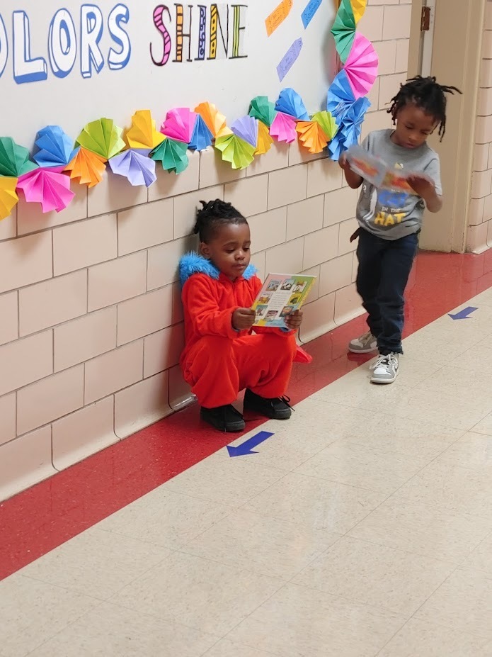 Two preschool students in the hallway looking through their new books