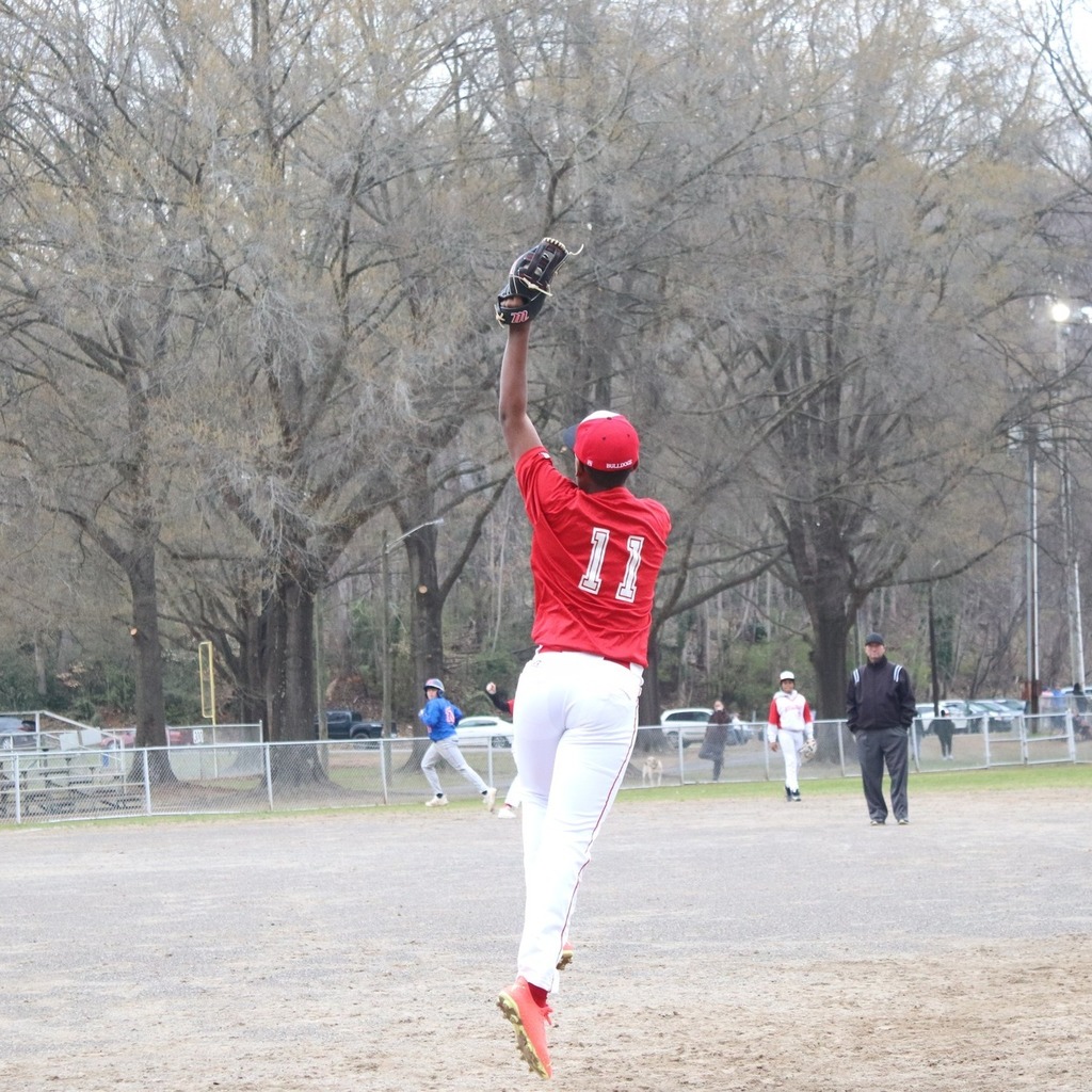 A middle school baseball player jumps up to make a catch