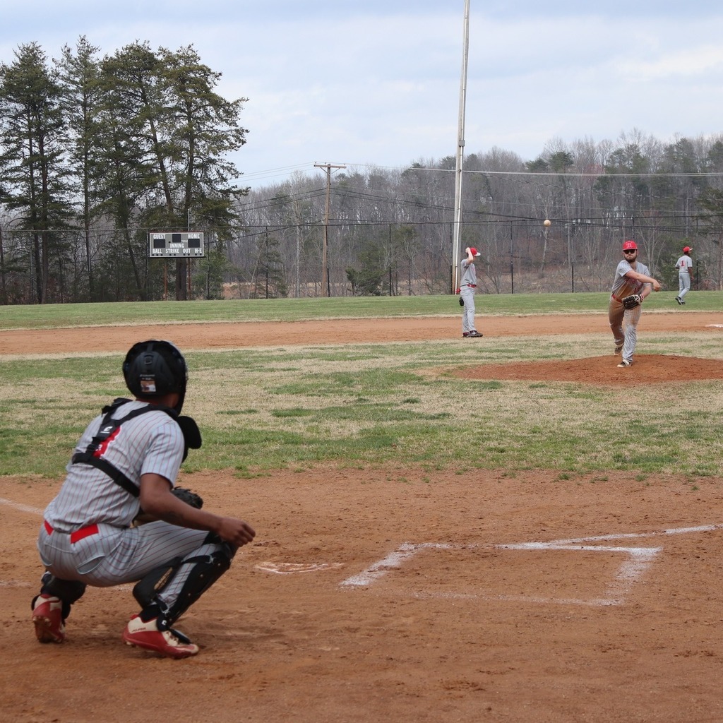 A high school baseball pitcher throws a ball to his catcher