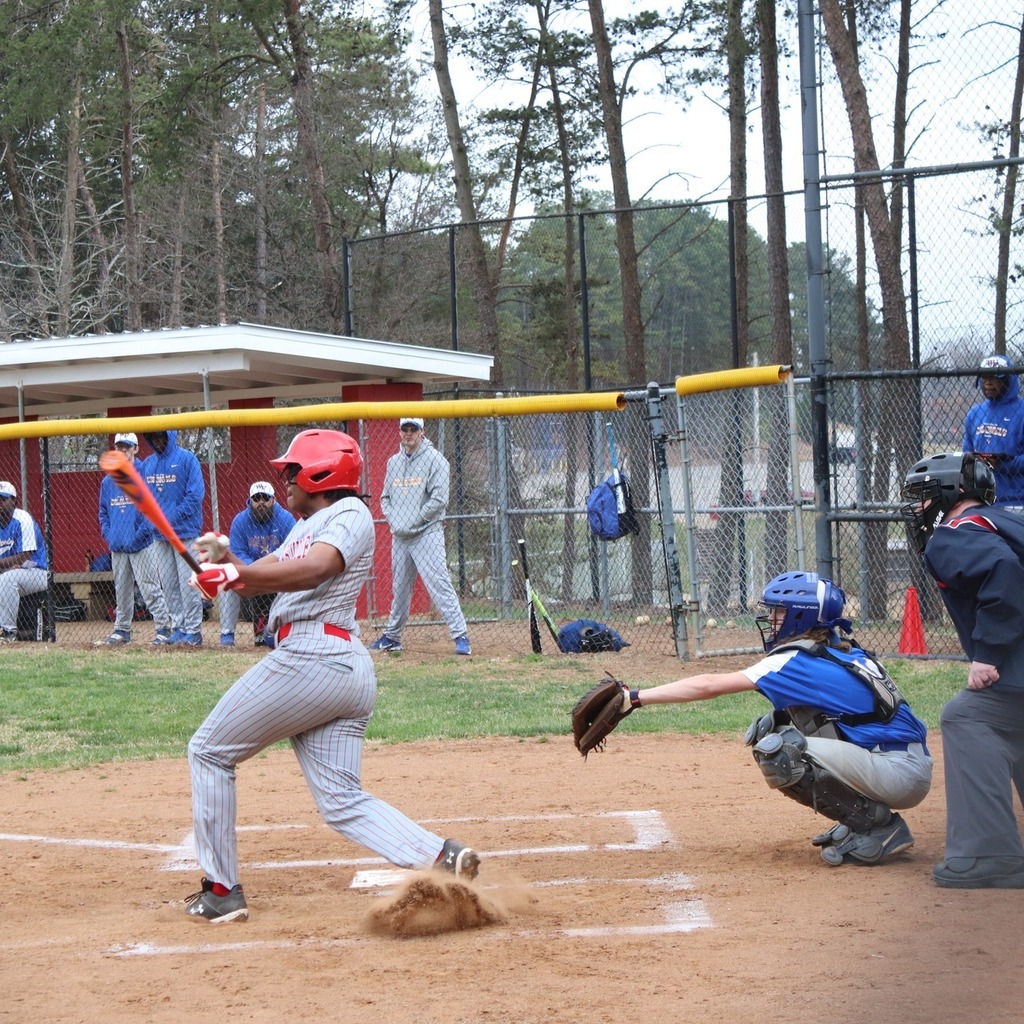 A high school baseball player swings at a pitch