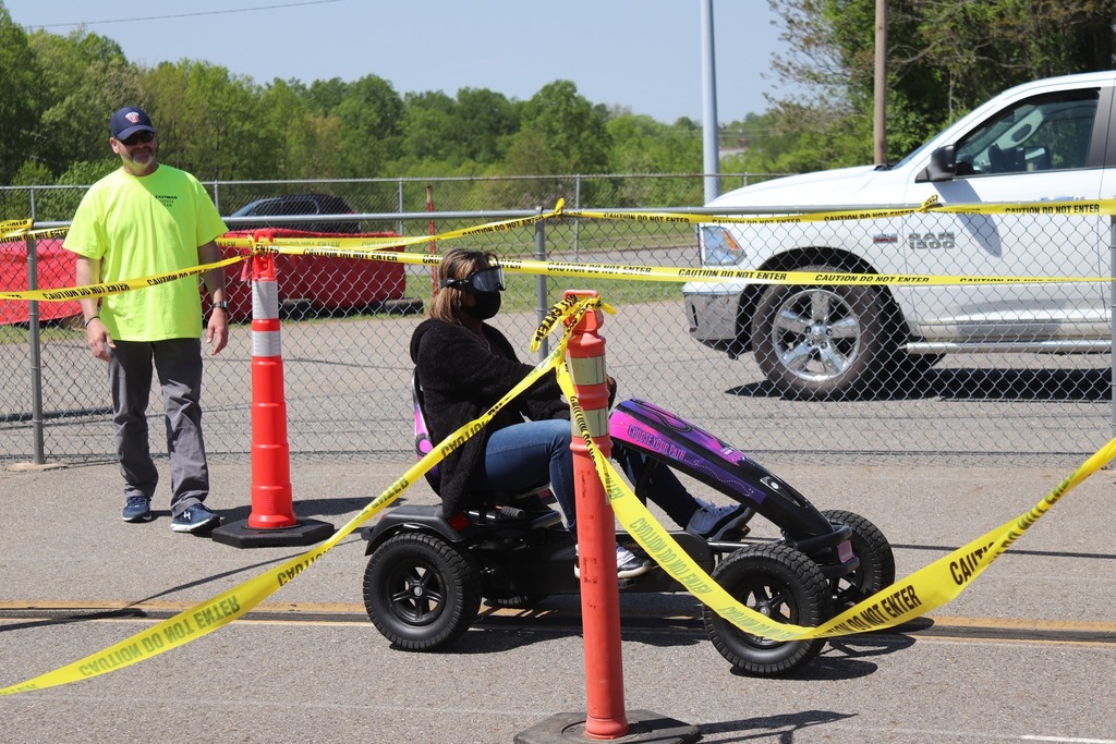 High school student wearing intoxication simulation goggles pedals a car through a course