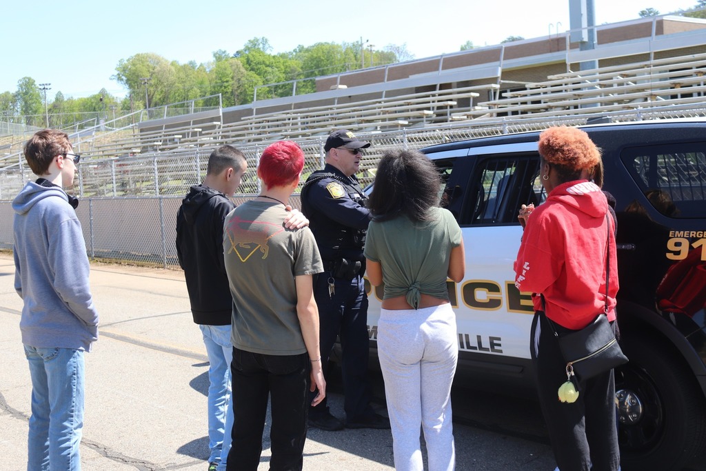 High school students gathered around a police car