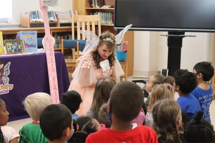 the Tooth Fairy leans down to talk with students 