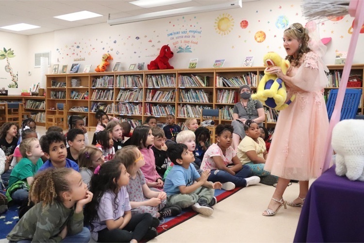 Students watch as The tooth fairy holds up a stuffed dog toy with fake teeth 