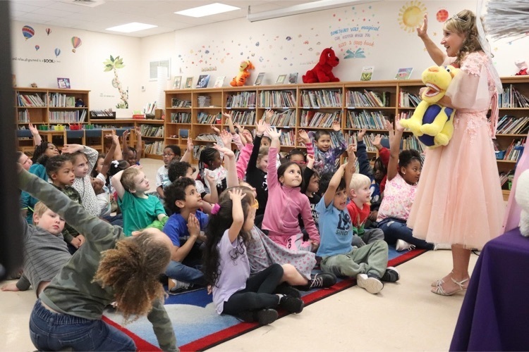 Students raise their hands during a presentation by the tooth fairy