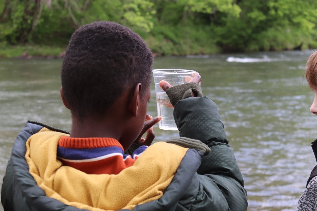 AHES students look at a brook trout in a plastic cup