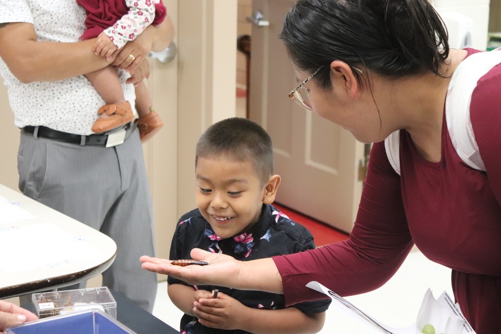 Clearview student smiles as his mother holds an insect from a museum display