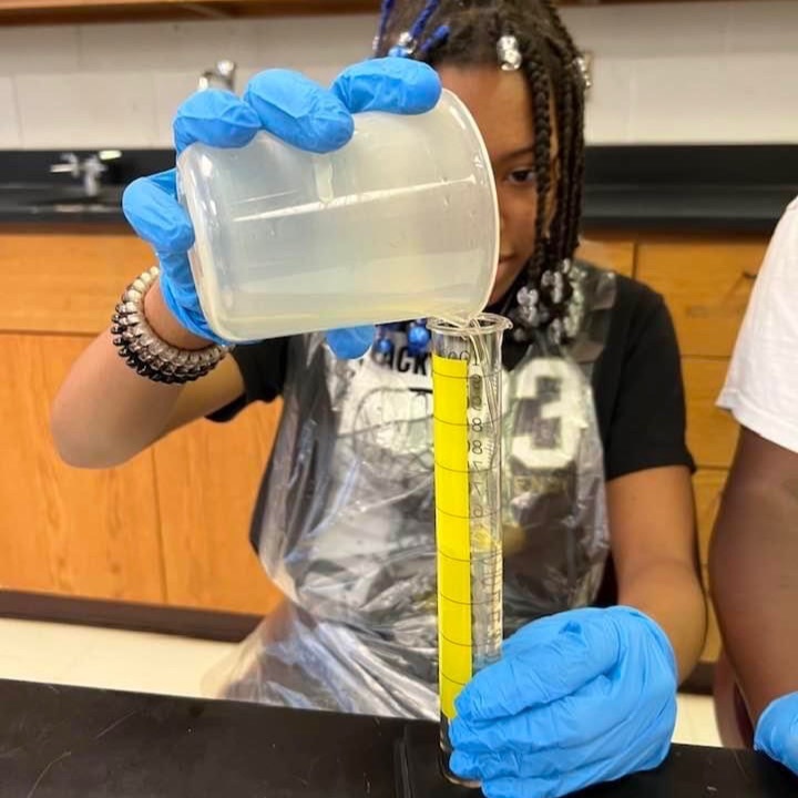 a student pours a substance into a test tube 