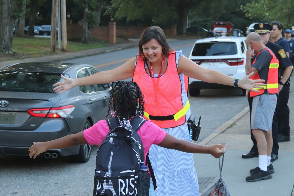PHES principal smiles as she opens her arms for a hug from a student