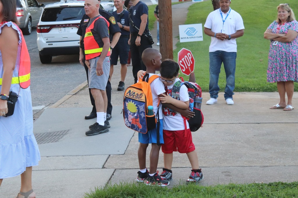 Two elementary students hug outside of school