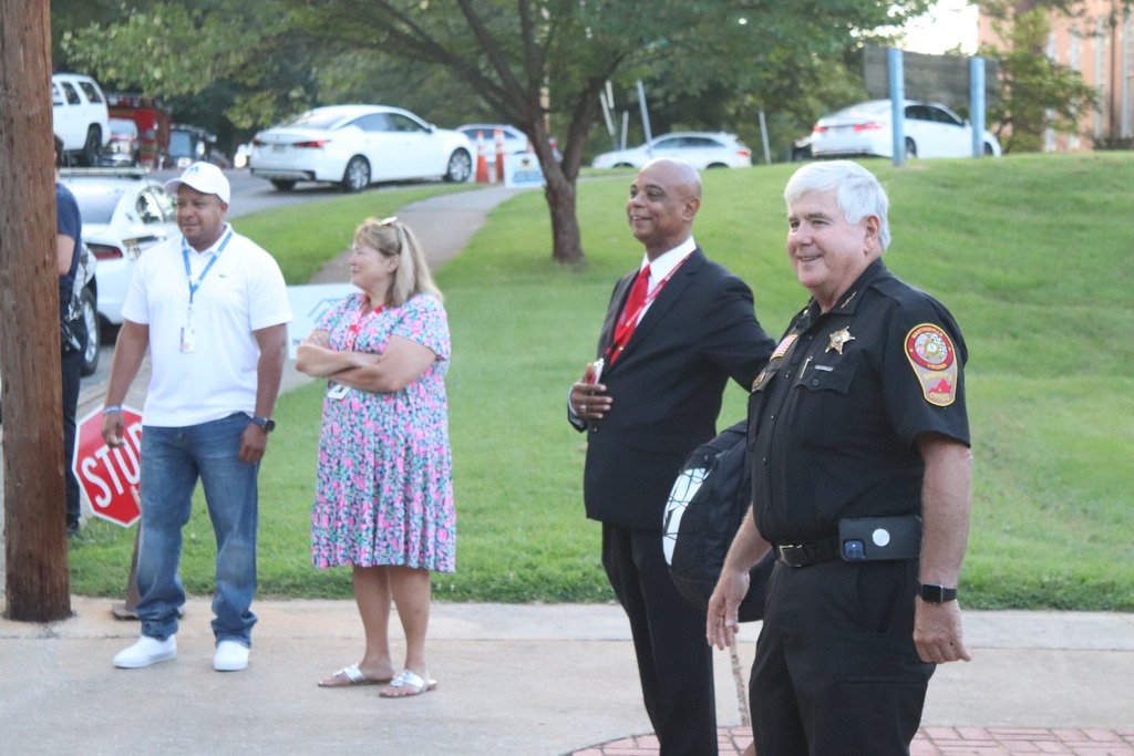 Martinsville mayor, school board chair, schools superintendent, and police chief all stand outside of a school to greet students